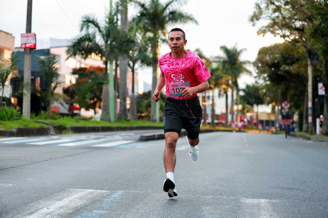 Energetic young man in pink sportswear running in a city marathon.
