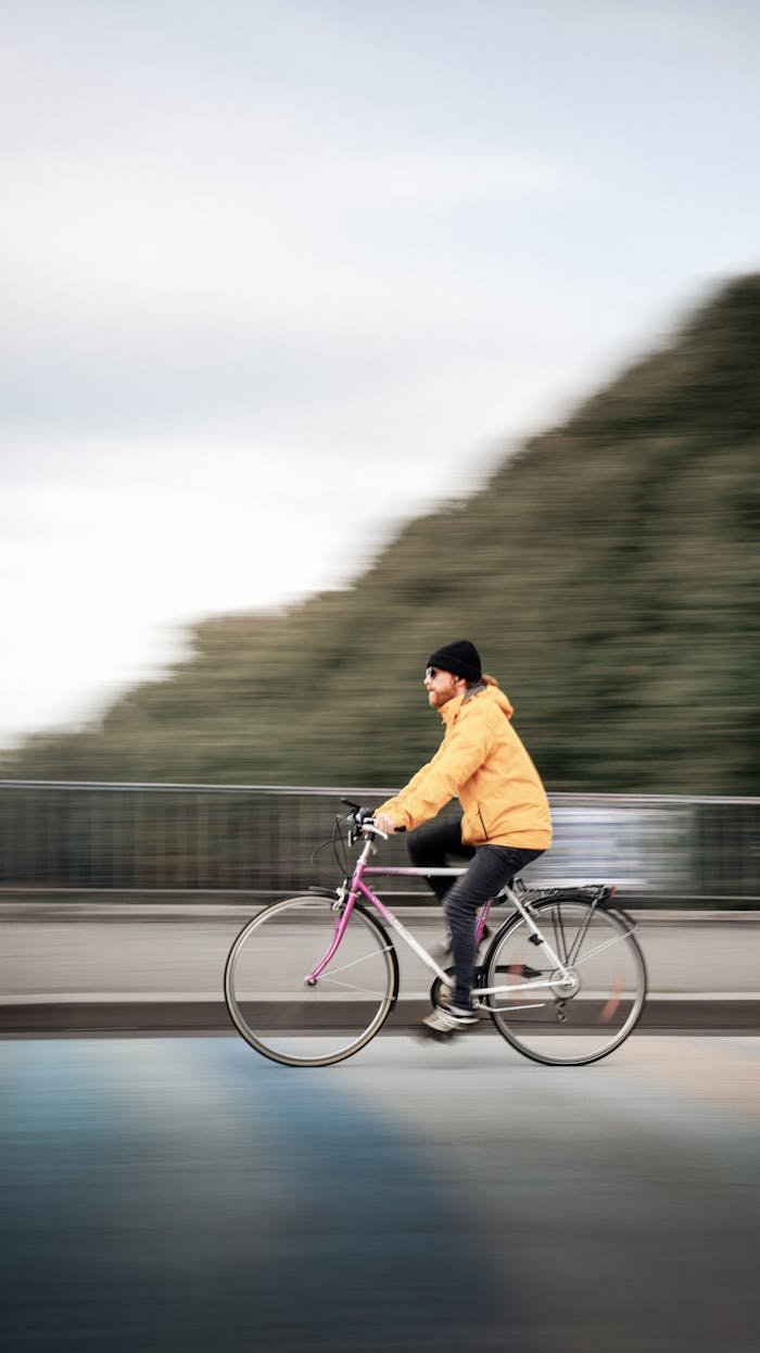 Person in a yellow jacket rides a bicycle across a bridge in Leipzig.